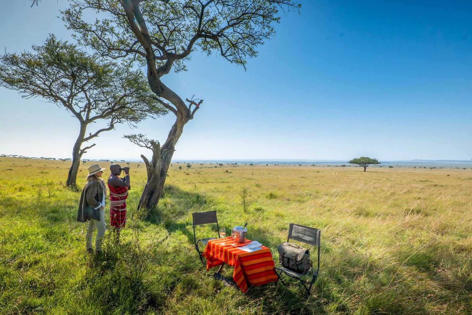 Guests enjoying sundowners with Maasai guides above the Mara