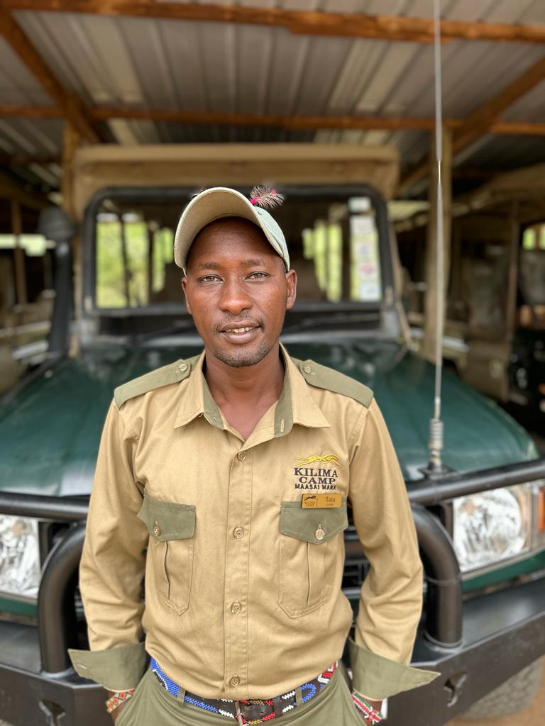 Tatu, Kilima Camp safari guide, standing by a safari vehicle